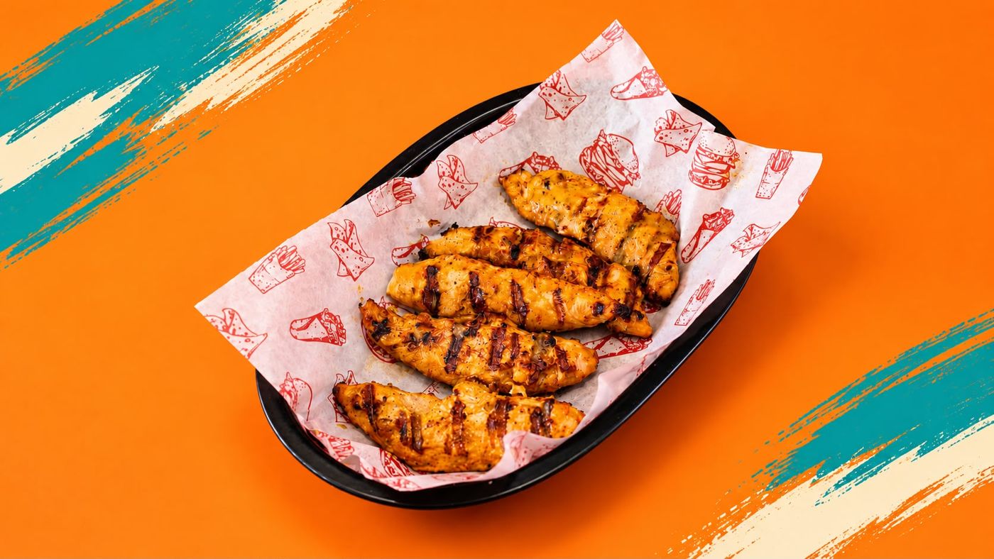 Flame-grilled chicken strips in a paper-lined basket