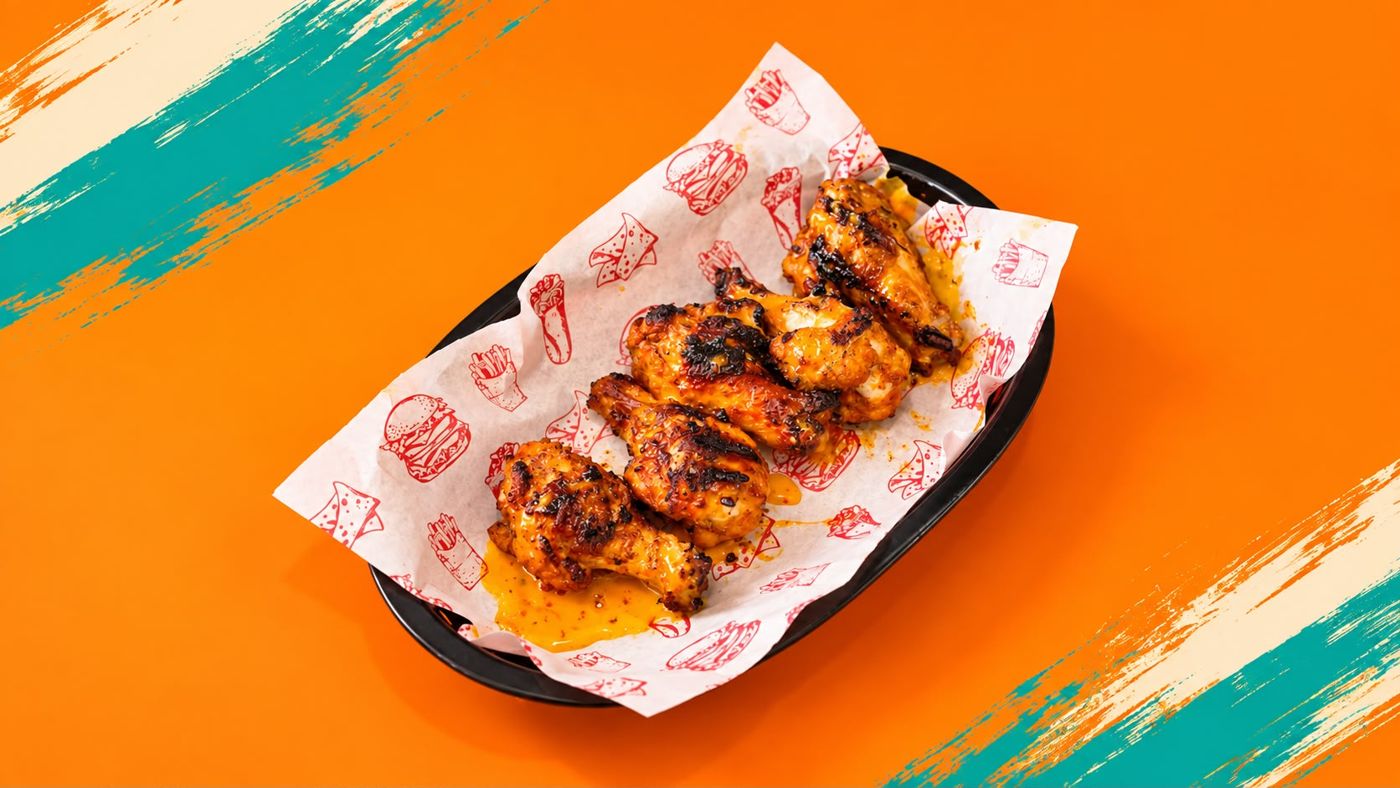 Flame-grilled chicken wings in a paper-lined basket